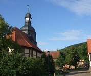 Blick auf eine Dorfstraße mit kleiner Kapelle und Fachwerkhäusern.