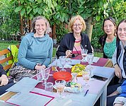 Teamfoto des Bür.A-Teams. Alle sitzen zusammen am Garten uns besprechen das Programm der Bür.A.