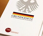 Ein Stapel Grundgesetz-Bücher liegen auf einem Tisch.