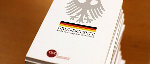 Ein Stapel Grundgesetz-Bücher liegen auf einem Tisch.