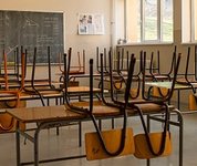Blick in altes Klassenzimmer. Die Stühle sind auf die Tische geräumt. Der Raum ist leer.