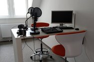 Tisch mit zwei Studoimikrophonen, Mischpult und PC. Hier werden die Podcastaufnahmen gemacht.